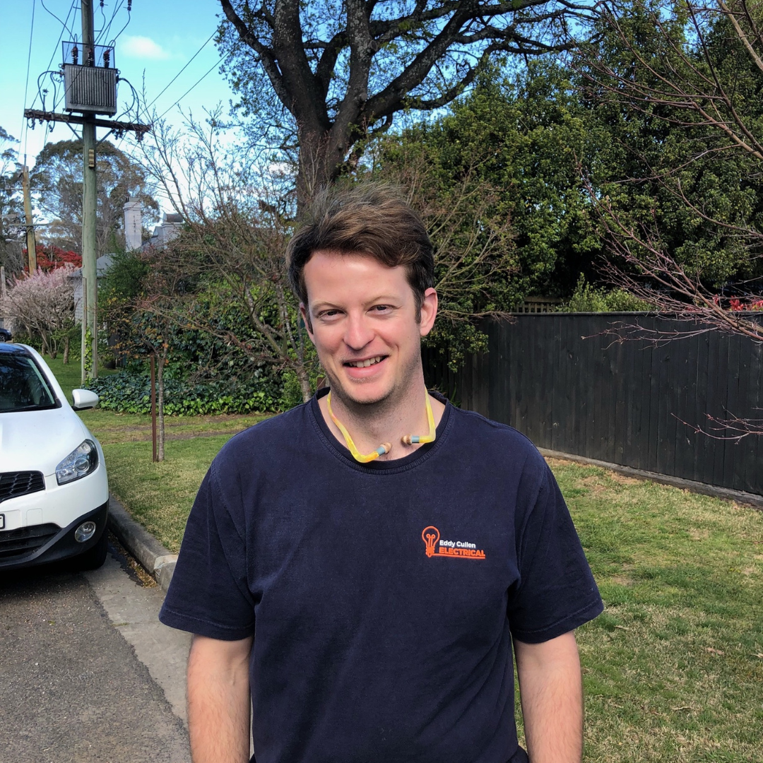 Eddy Cullen, local Bundanoon electrician, standing outdoors in uniform on a residential street