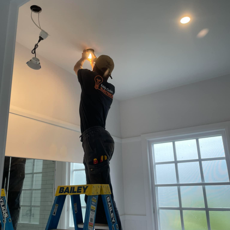 This image showcases a Residential Electrician from Eddy Cullen performing a light installation within a bathroom on a Bowral property.
